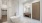 penthouse bathroom with freestanding soaking tub next to a tiled accent wall, vanity with framed mirror and brown wood cabinets with linen closet