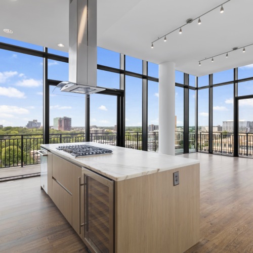 apartment kitchen and living area with kitchen island with gas stove and wine fridge, wood flooring, and floor to ceiling windows with views of Charlotte apartment kitchen and living area with kitchen island with gas stove and wine fridge, wood flooring, and floor to ceiling windows with views of Charlotte