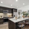 kitchen photo with white countertops, dark wood cabinets, neutral wood flooring, and counter height island with stools 