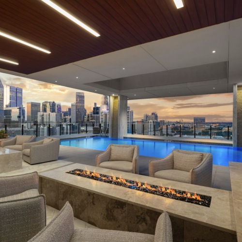 A beautiful community at the heart of all your passions two fire places with four chairs surrounding the fireplaces with the pool and skyline in the background